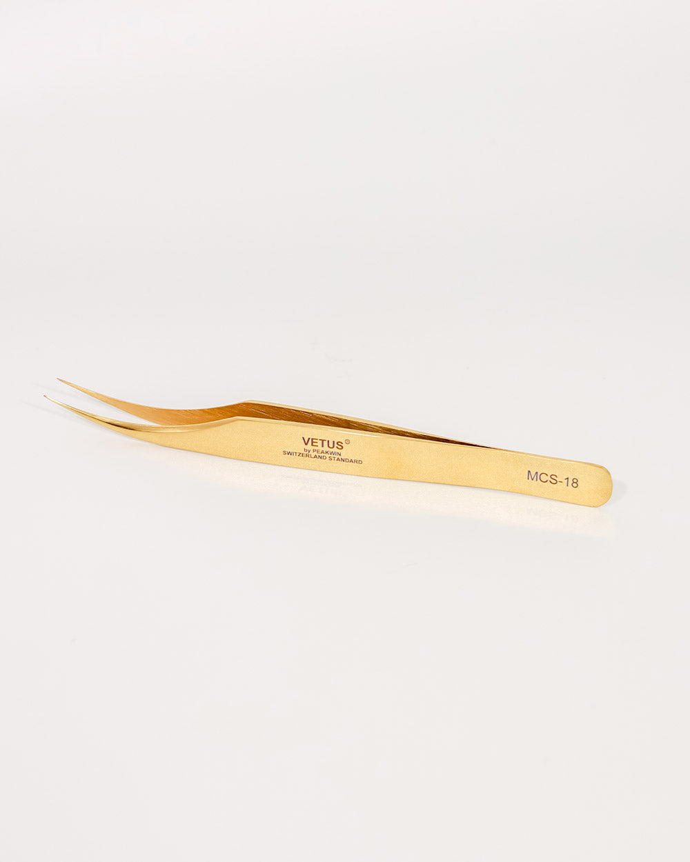Gold-colored tweezers with 'Vetus' branding on a light gray background