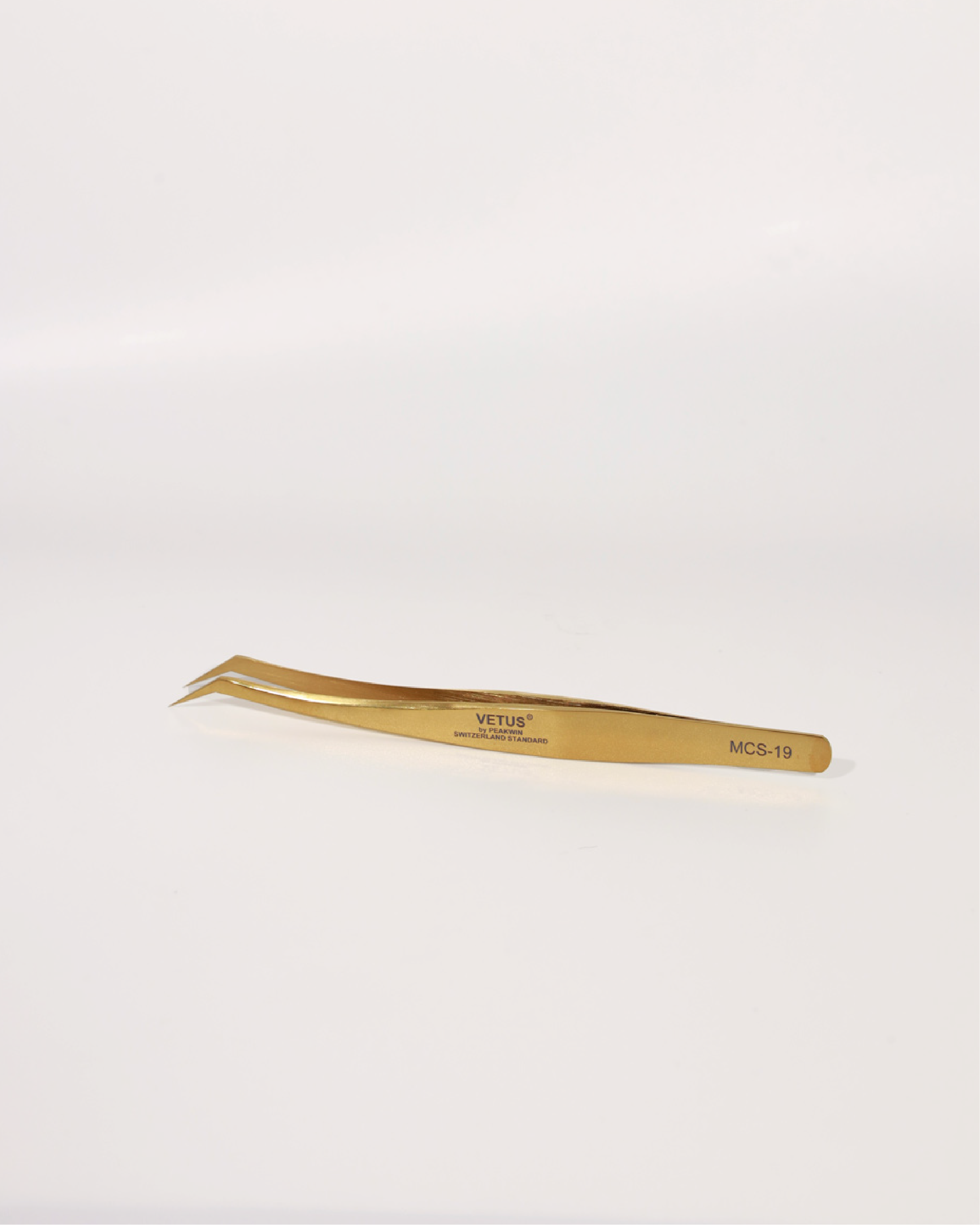 Gold-colored tweezers on a white background